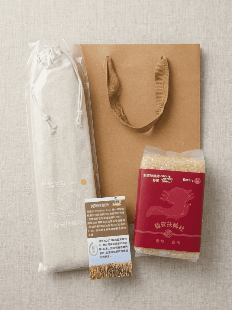 EatMe parboiled rice Rotary Club branded gift set featuring a custom red-labeled rice package printed with the Rotary "Create Lasting Impact" slogan and Long-An Club logo, presented with a linen drawstring pouch, kraft paper bag, and a product introduction card. 益米預熟米扶輪社客製禮品組合，包含印有「創造持恆的影響」口號與龍安扶輪社標誌的紅色客製標籤米包、亞麻束口袋、牛皮紙手提袋，以及一張產品介紹卡。